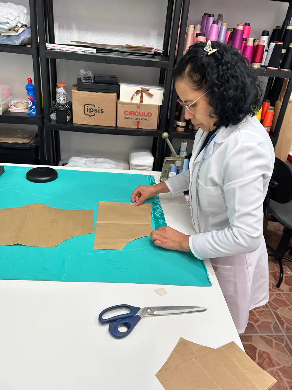 Costureira cortando tecido de roupa fitness com molde de papel
